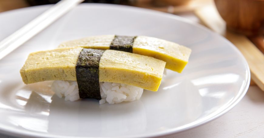 due nigiri con uovo omelet, o tamago nigiri, servi su un piatto in un ristorante di sushi giapponese